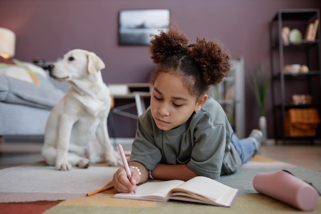 young girl working on notebook with puppy